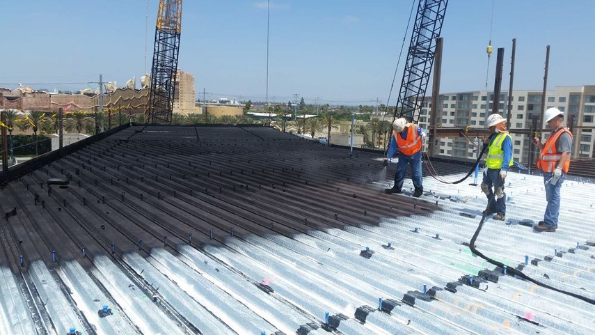 WetSuit application specialist spraying a seamless membrane on a rooftop